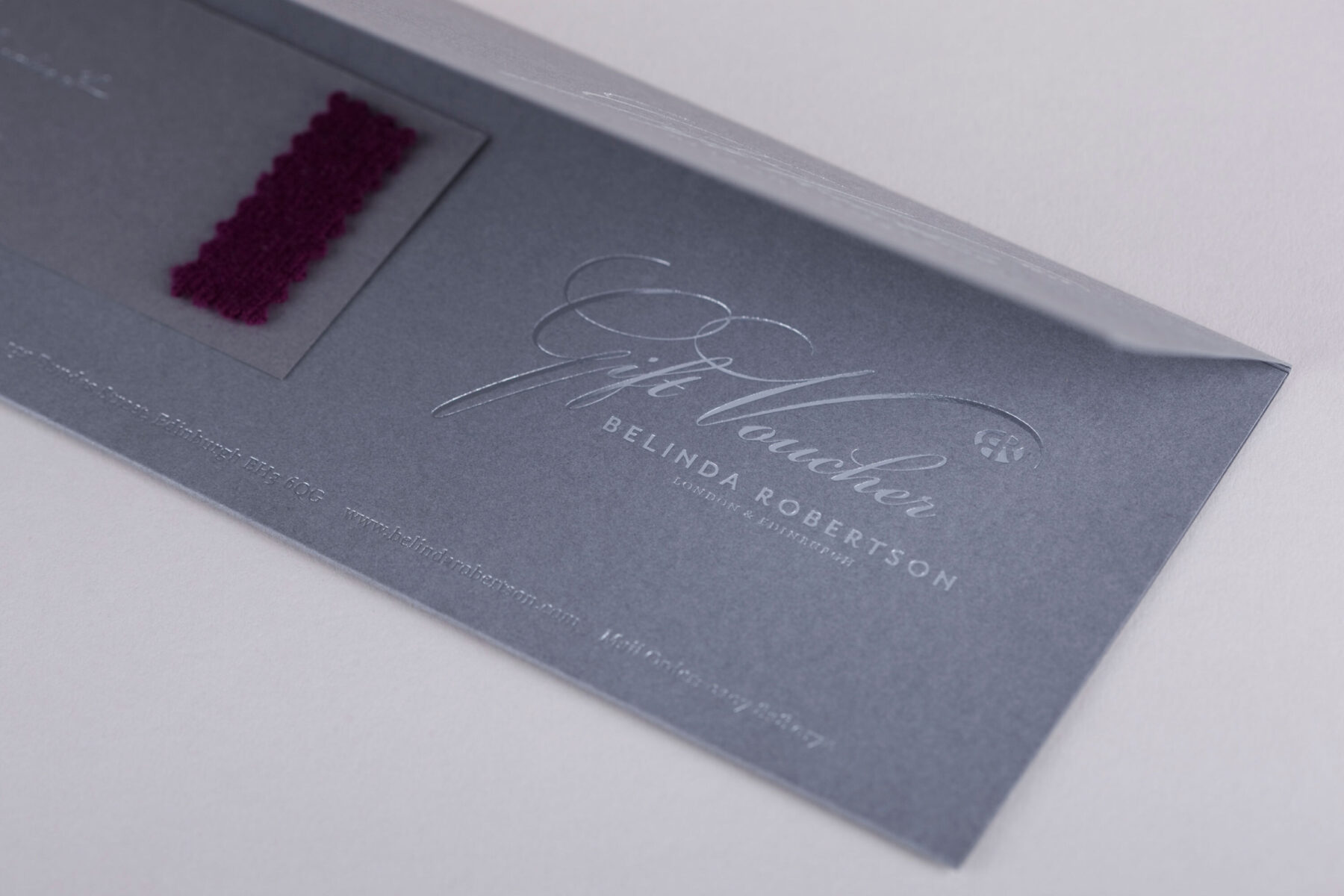 Inside of Belinda Robertson gift voucher. Grey card gift vouchers with silver foil blocked type and coloured cashmere swatches attached to each voucher.